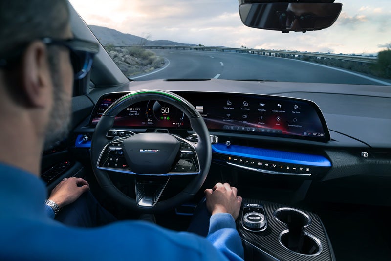 Front View of the 2026 OPTIQ-V Driving Through the Dusk Utilizing its Headlights | Waldorf Cadillac in Waldorf MD