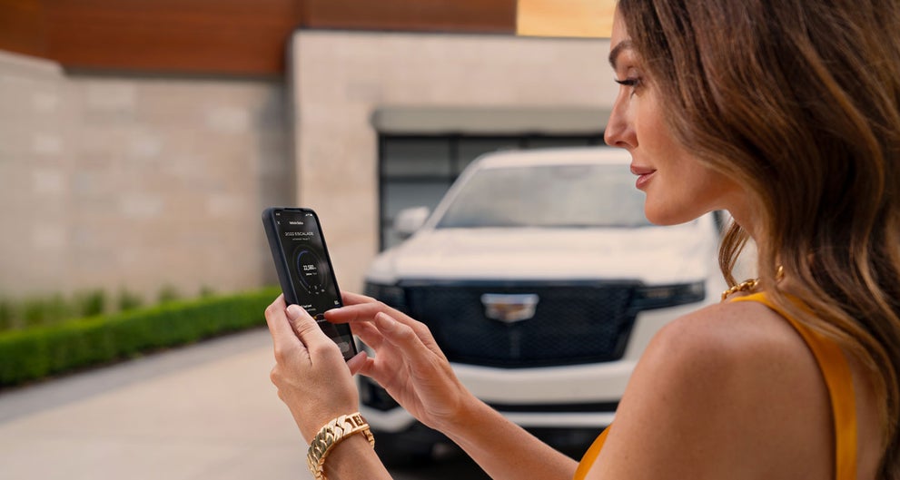 lady checking her mobile with a Cadillac vehicle background | Waldorf Cadillac in Waldorf MD